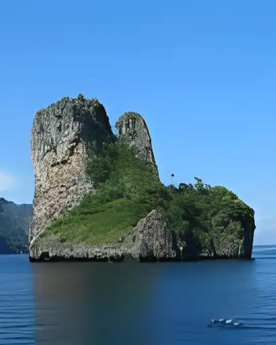 a small limestone island with 2 towering cliffs, covered by tropical vegetation