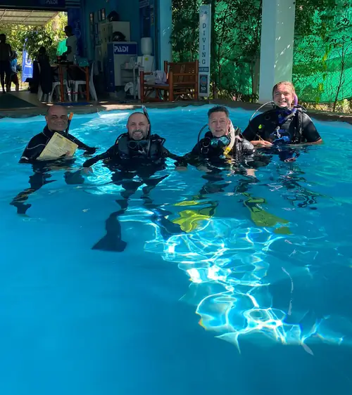 SCUBA diving instructors and students pose for a photo while in a covered swimming pool