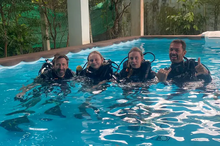 an instructor and 3 students learning scuba diving in a swimming pool