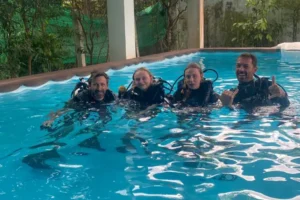 An instructor with a father and his 2 daughters during confined water scuba diver training in a training pool