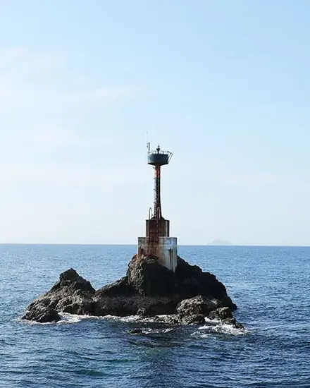a light beacon on a rocky outcrop surrounded by ocean at Shark Point dive site in Krabi Thailand