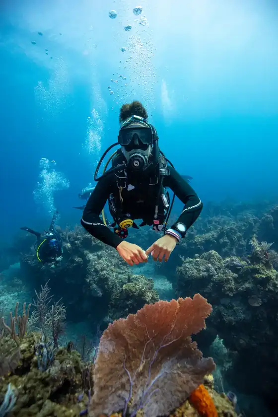 A SCUBA diver poses for the camera over a coral reef